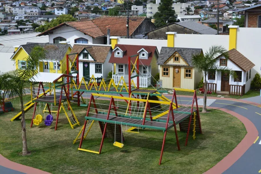 Mini cidade infantil em condomínio com playground de madeira, casinhas temáticas e pista lúdica ao ar livre